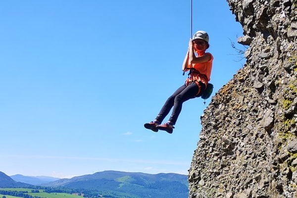 ClimbScotland 28 A young person being lowered off a rock face during a climbing session.
