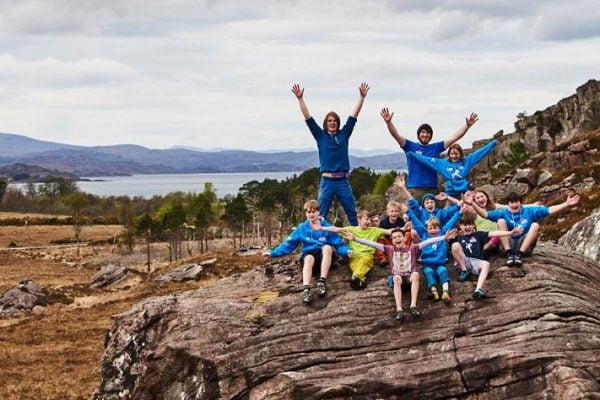 About ClimbScotland 2 A group of people standing on top of a rock with their hands in the air after a day out climbing.