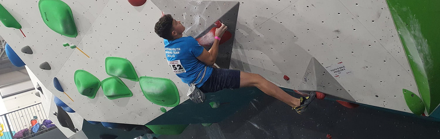 Young man taking part in a bouldering competition at an indoor wall