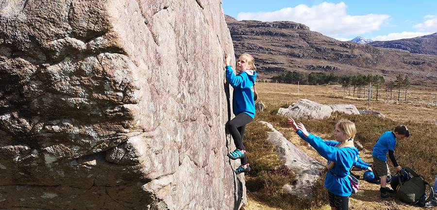 Young girl bouldering on a rock outdoors